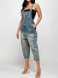 Person wearing denim overalls on a plain background