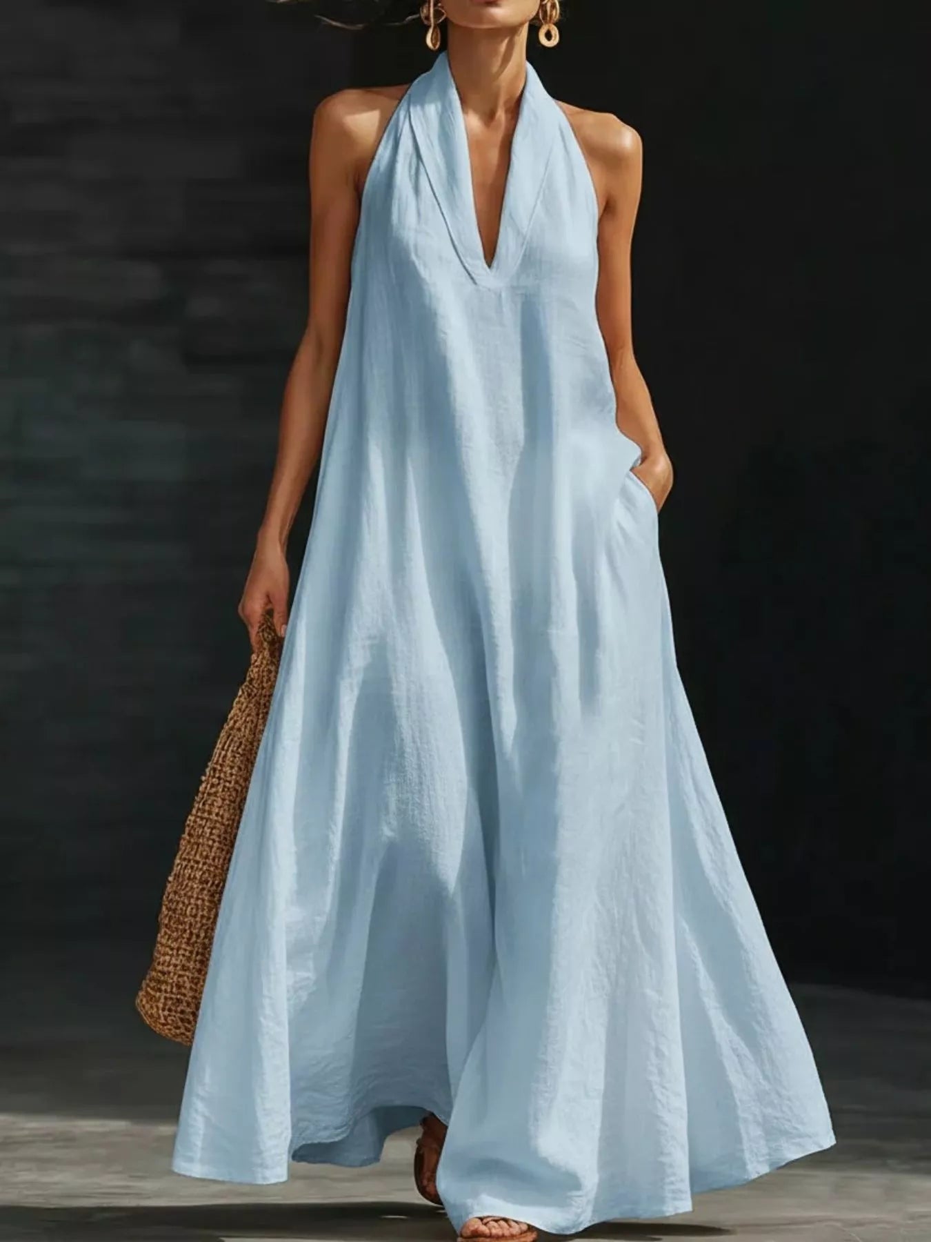 Woman wearing a light blue halter neck dress against a dark background