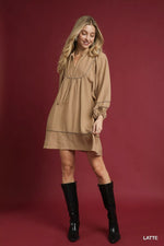 Woman wearing a beige dress and black boots on a red background