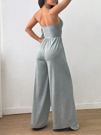 Person wearing a gray jumpsuit against a white wall.