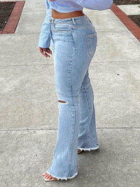 Person wearing light blue jeans and a cropped top on a sidewalk.
