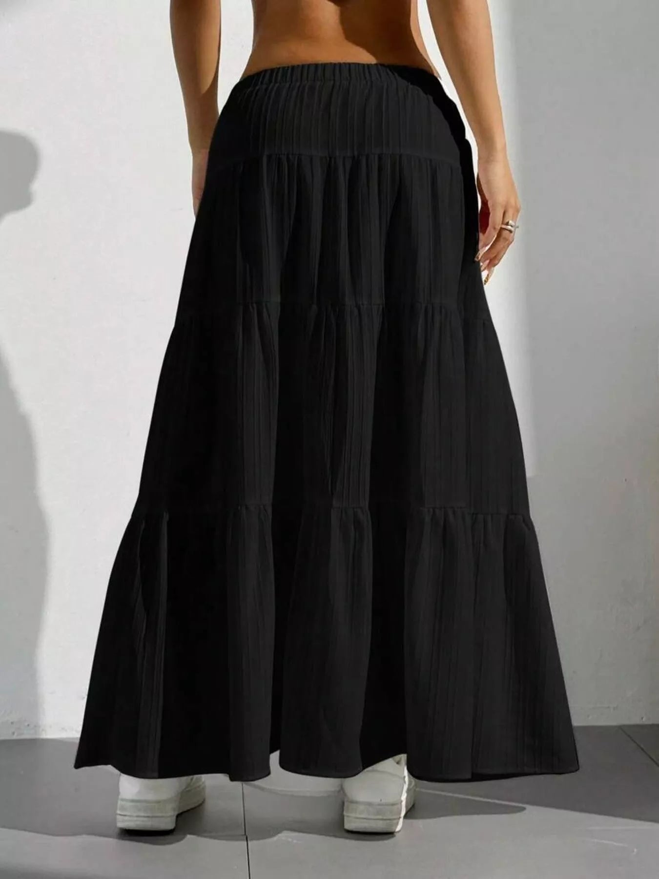 Black tiered skirt worn by a person on a plain background