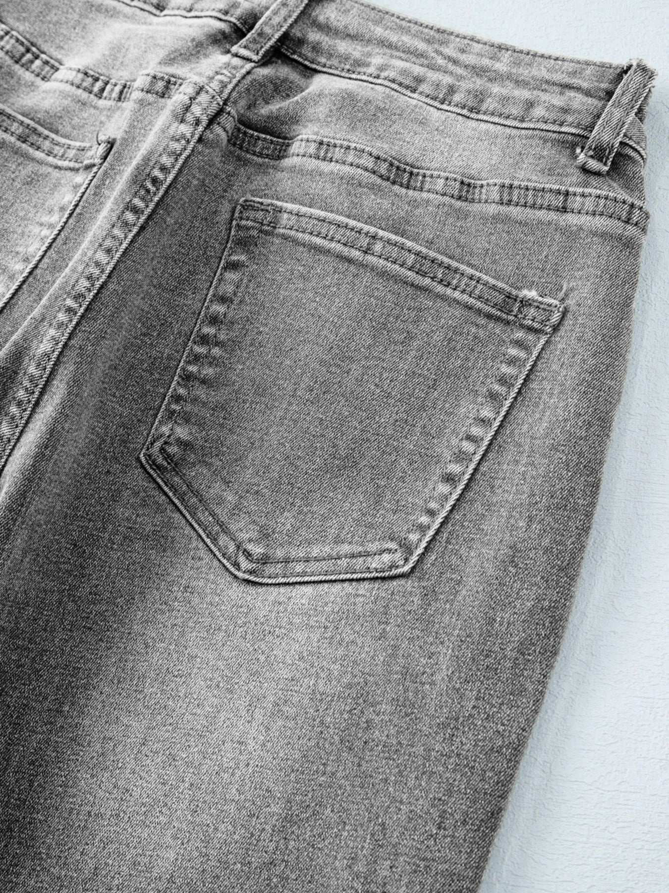 Close-up of gray jeans with a pocket on a light gray background