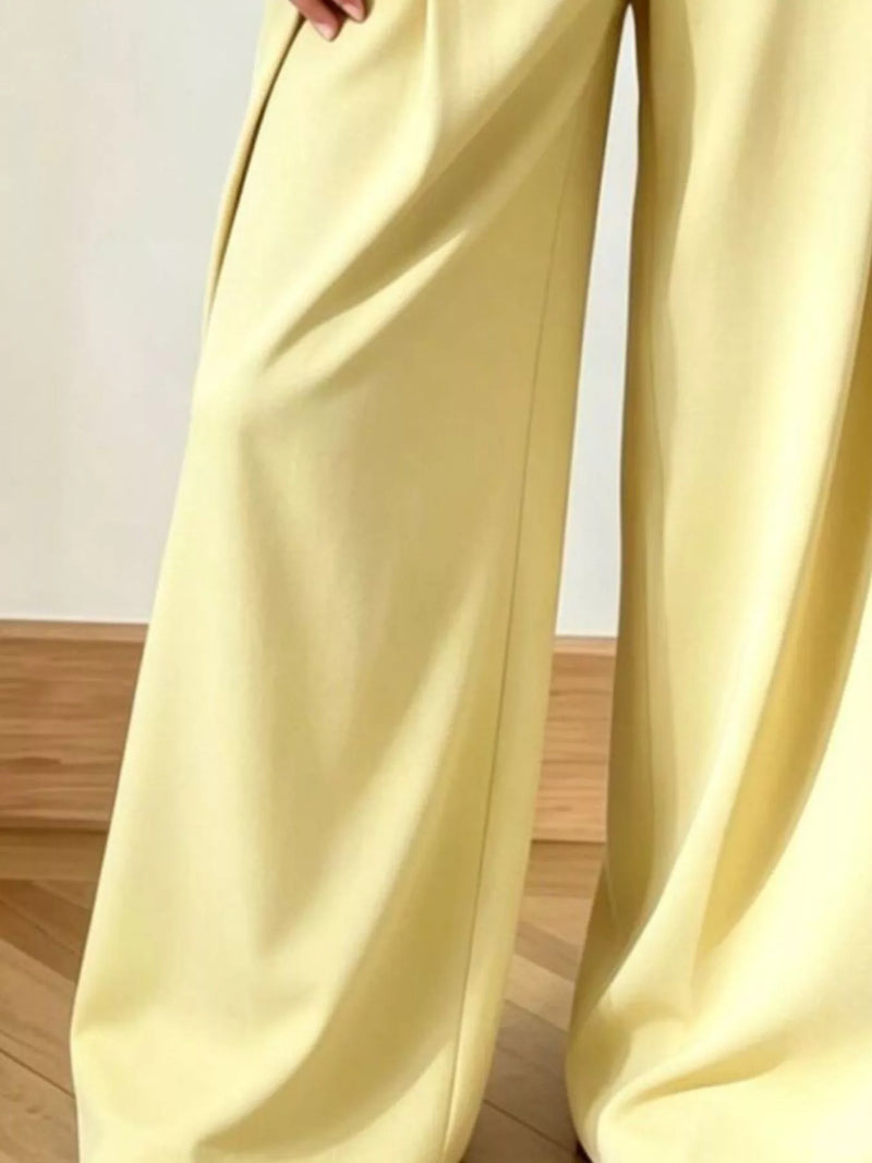 Light yellow wide-leg pants on a wooden floor.