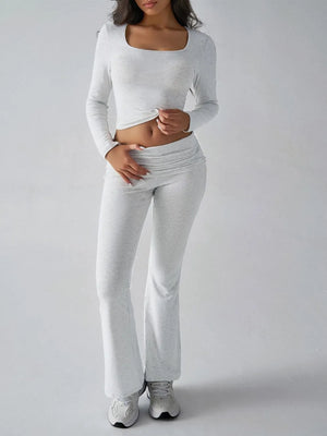 Person wearing a white long-sleeve top and gray sweatpants on a plain background