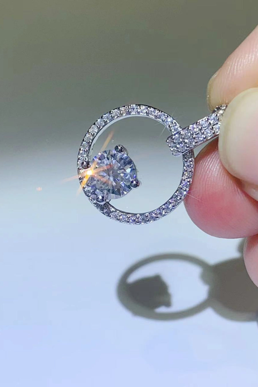 Close-up of a silver ring with a heart-shaped gemstone held by a hand.