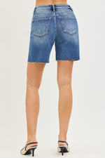 Blue denim shorts worn by a person on a white background