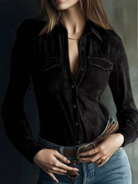 Person wearing a black velvet shirt with a deep neckline against a dark background