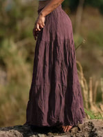 Person wearing a long, flowing purple skirt standing outdoors with a natural background.
