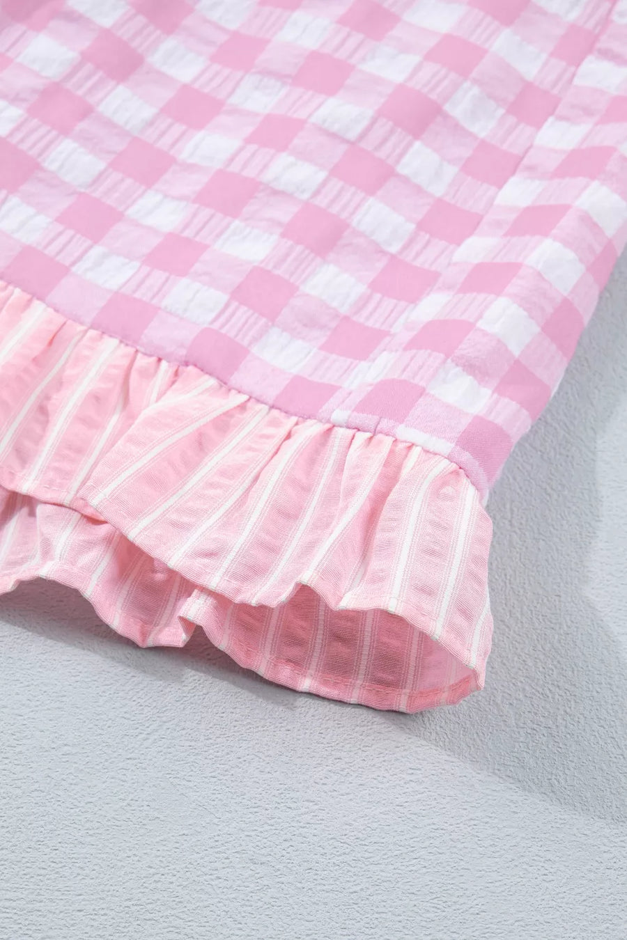 Close-up of a pink and white checkered fabric with ruffled edge on a light gray background