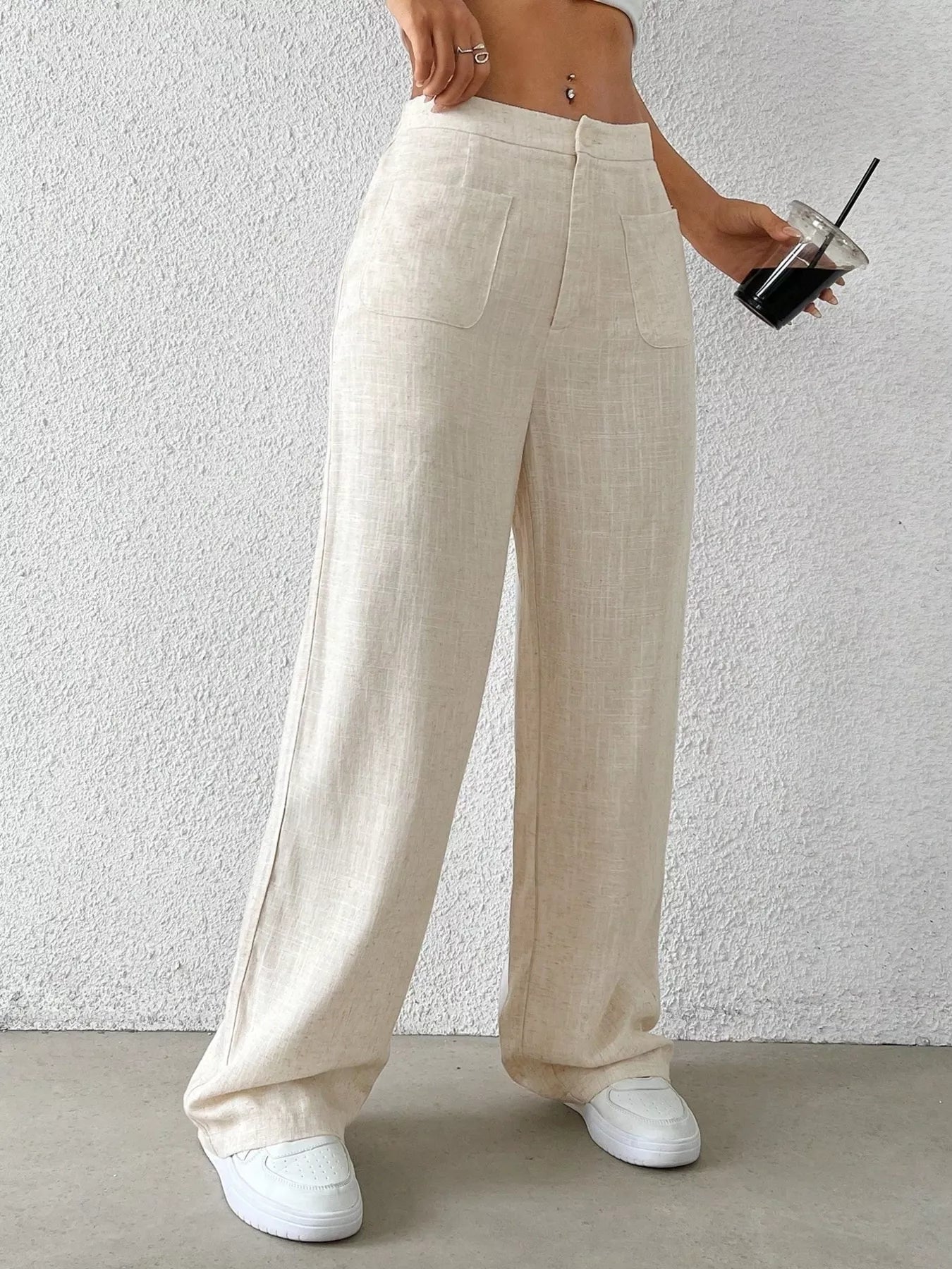 Person wearing beige wide-leg pants against a white wall