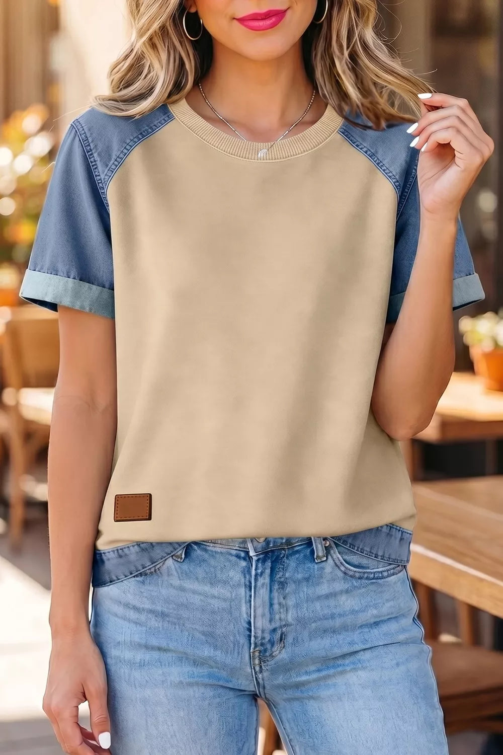 Woman wearing a beige and blue top with jeans in an outdoor setting