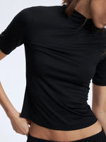 Person wearing a black short-sleeve top against a light gray background
