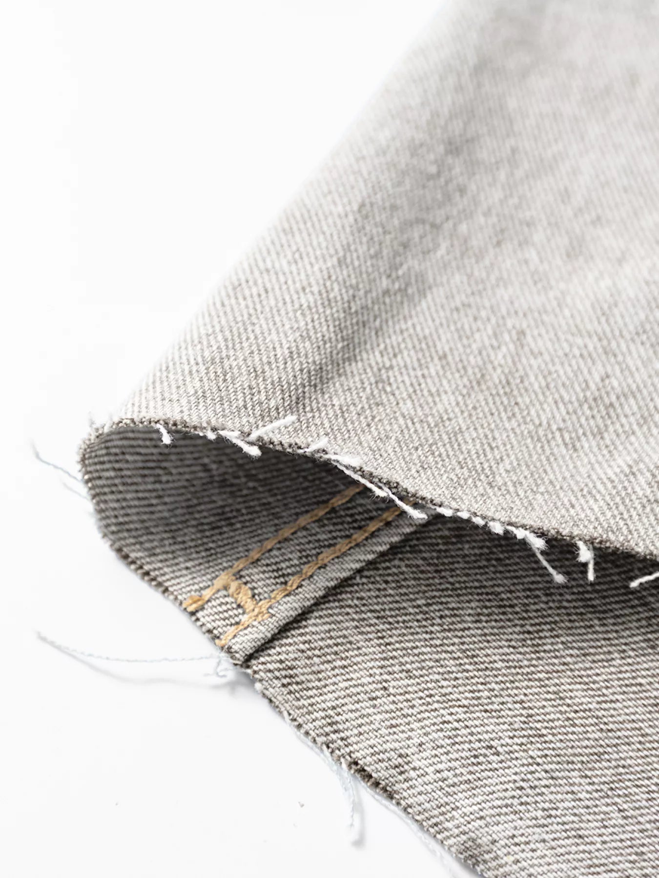Close-up of gray denim fabric with a brand label on a white background