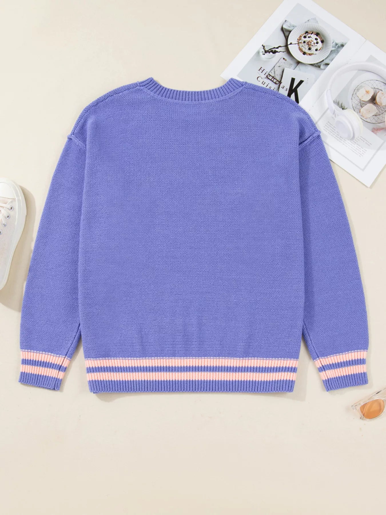 Blue sweater with striped cuffs on a light background