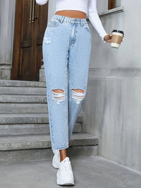 Person wearing ripped light blue jeans and white sneakers, holding a coffee cup on concrete steps.