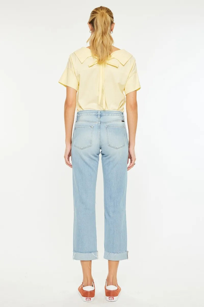 Person wearing a yellow top and light blue jeans on a white background