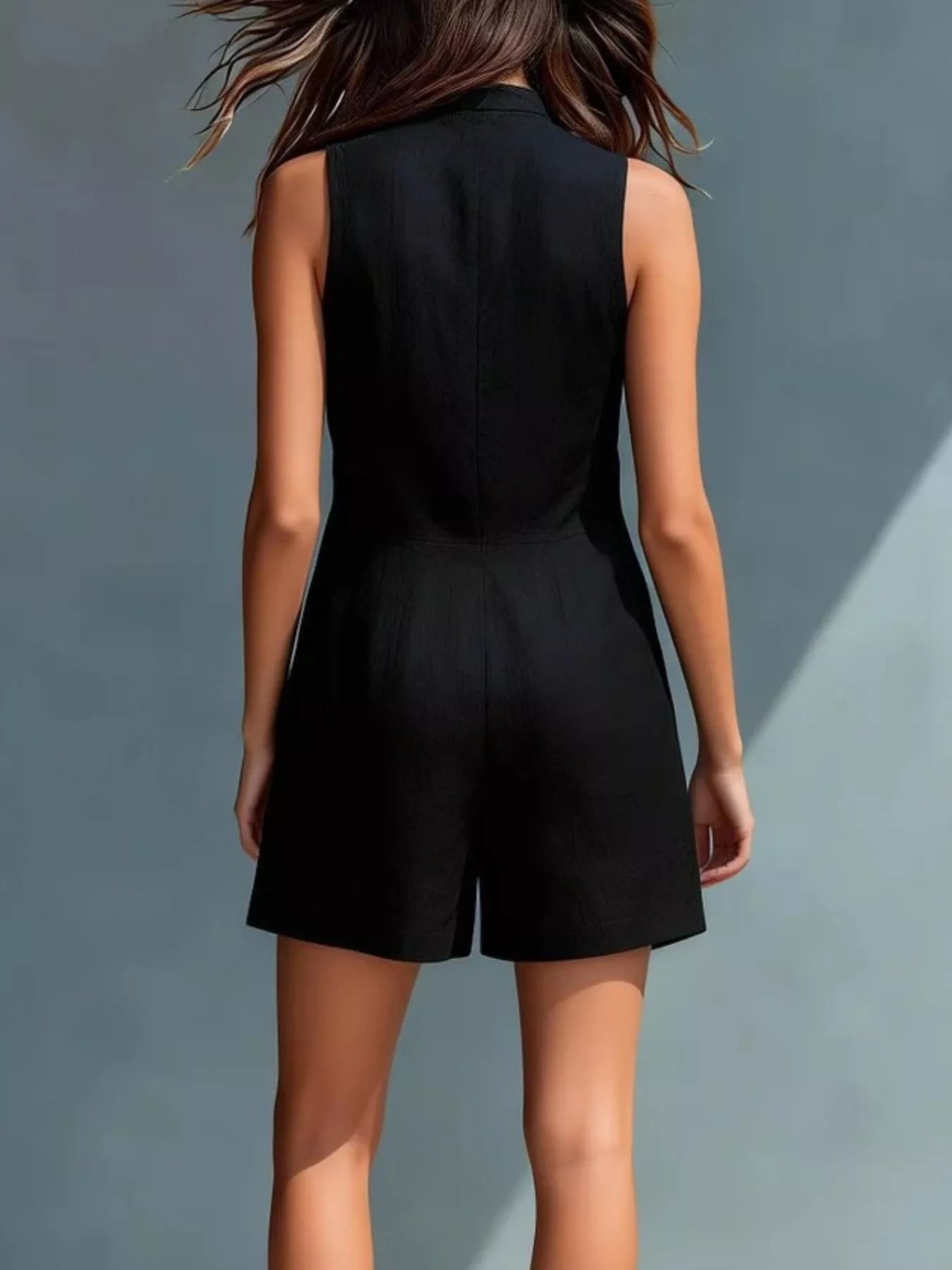 Person wearing a black sleeveless jumpsuit against a gray background