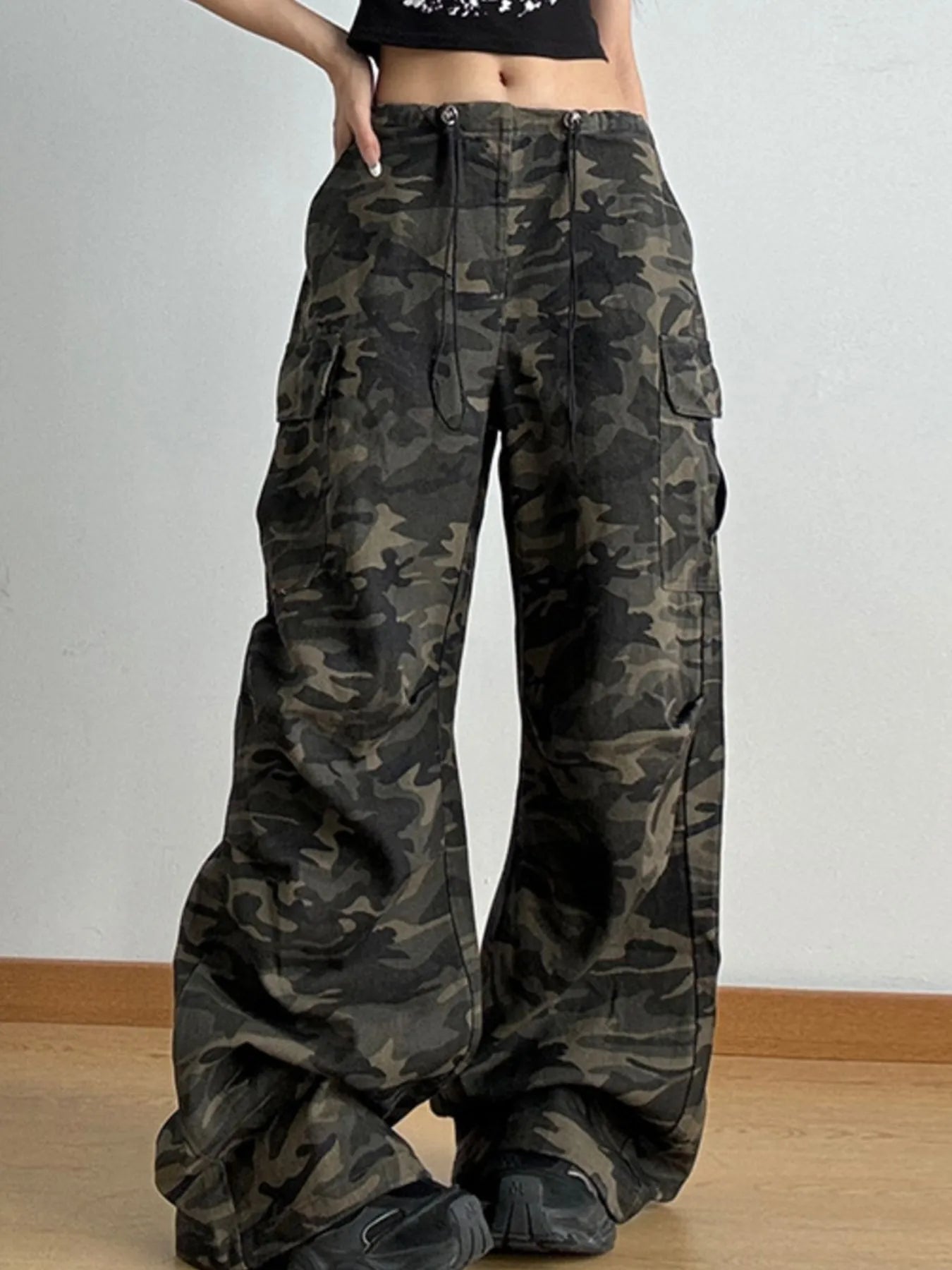 Camouflage pants worn by a person on a plain background