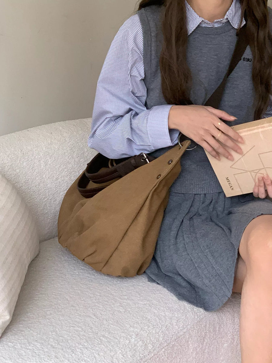 Person sitting on a couch holding a brown bag and a wooden item.