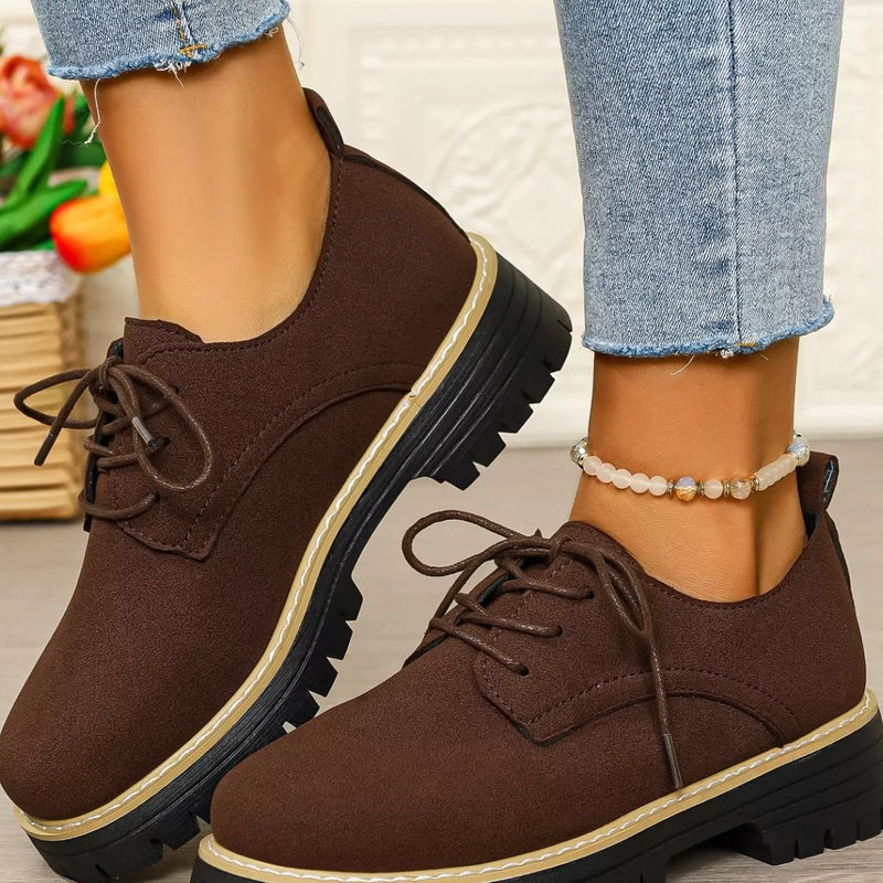 Brown suede shoes worn with light blue jeans on a neutral background