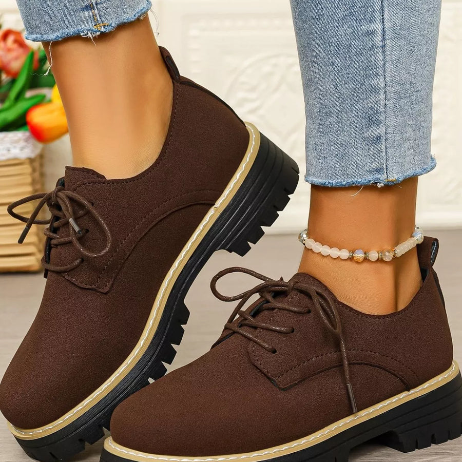 Brown suede shoes worn with light blue jeans on a neutral background