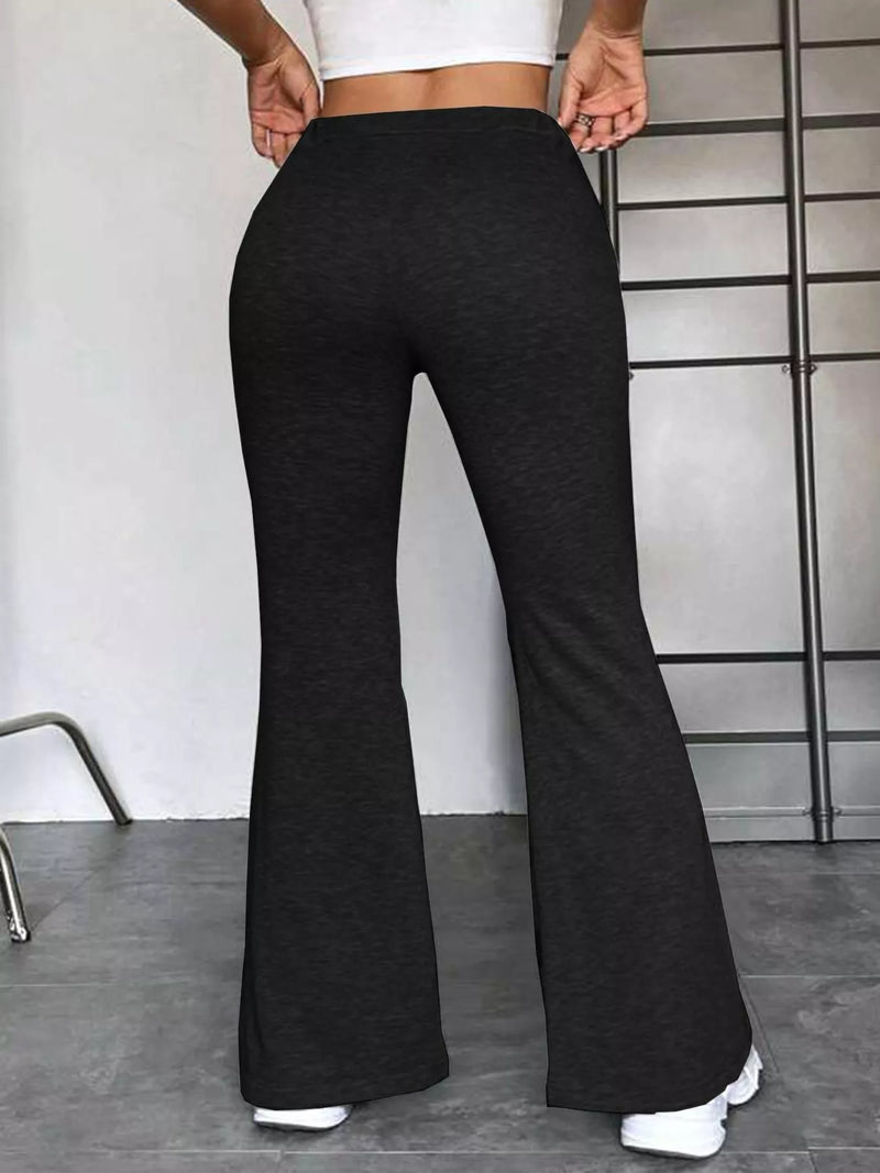 Person wearing black flared pants and a white top against a minimal background