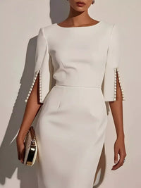 White dress with pearl embellishments on sleeves against a neutral background