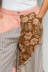 Person wearing a skirt with a floral pattern and striped layers on a plain background