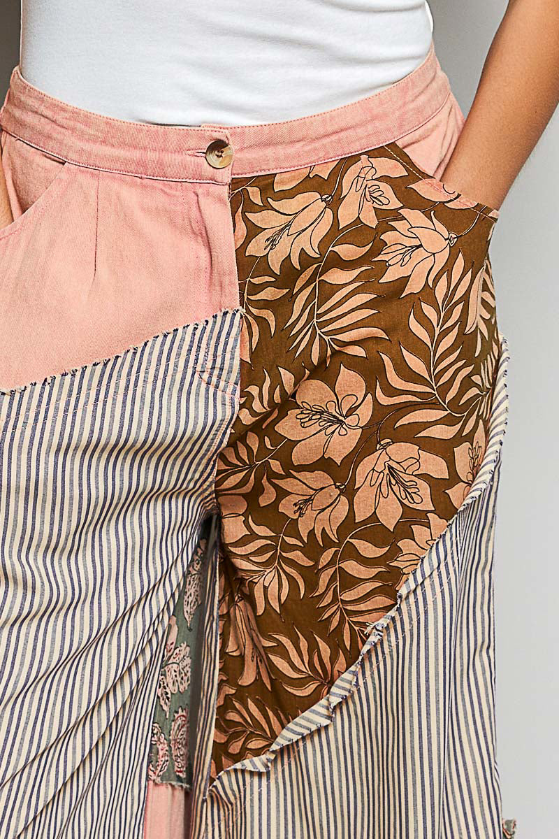 Person wearing a skirt with a floral pattern and striped layers on a plain background