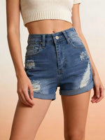 Person wearing blue denim shorts with a beige background