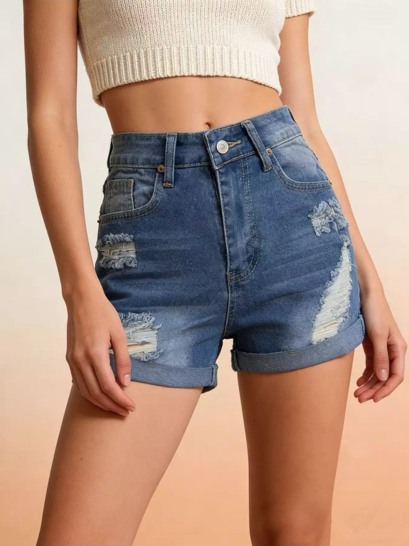 Person wearing blue denim shorts with a beige background