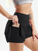 Person wearing black athletic shorts with a pocket, holding a phone.