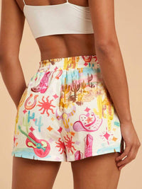 Colorful shorts with a cartoonish design worn by a person on a beige background