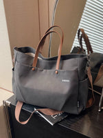 Gray tote bag with brown handles on a surface