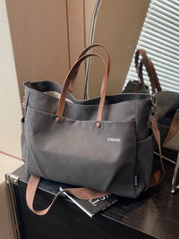 Gray tote bag with brown handles on a surface
