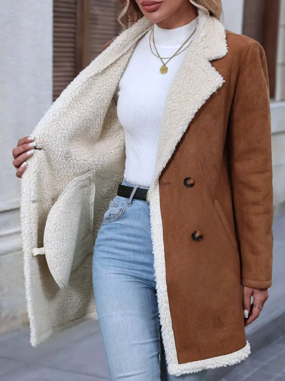 Person wearing a brown coat with white fur lining, white top, and light blue jeans.