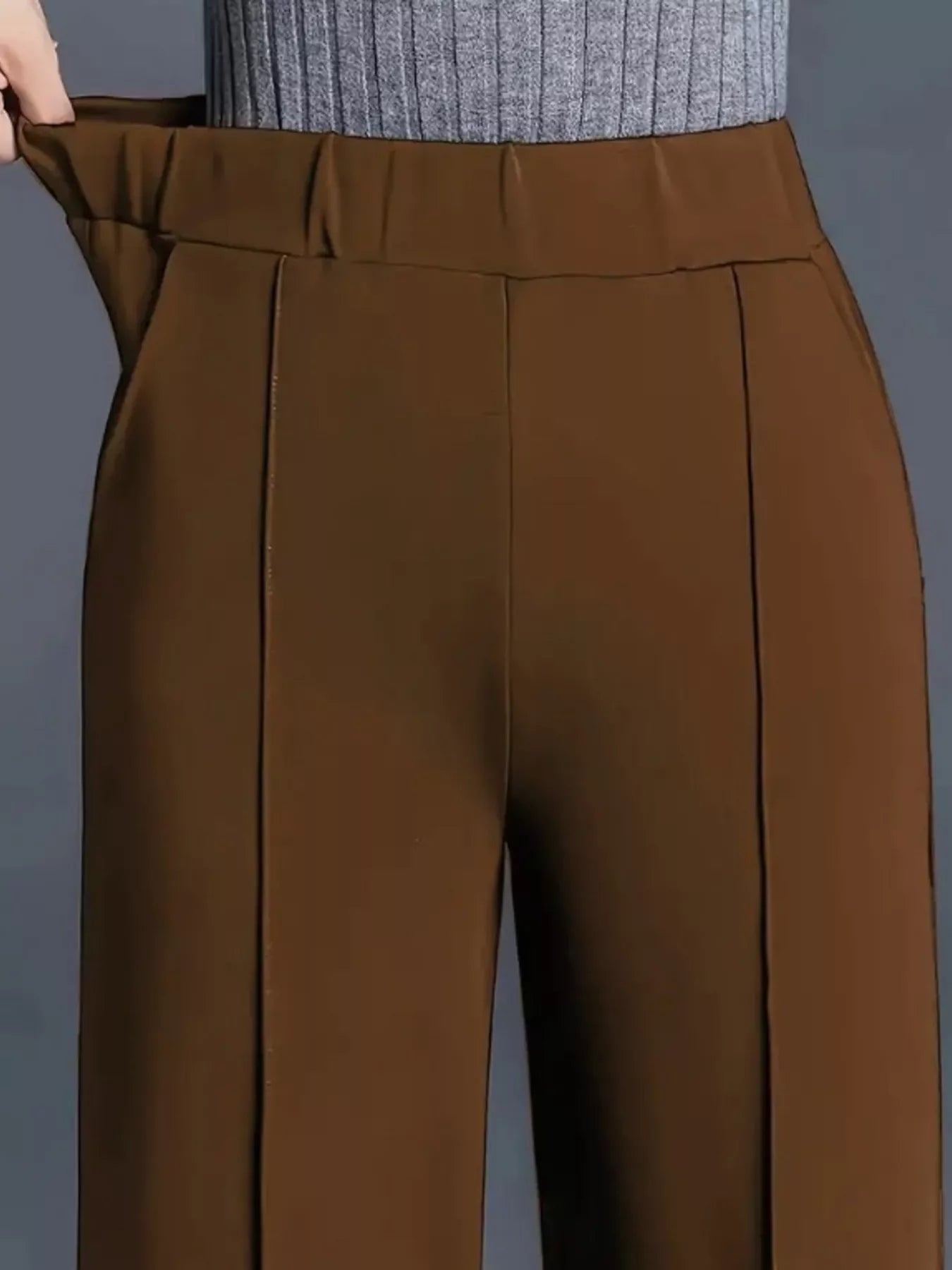 Brown pants being worn against a gray background