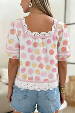 Woman wearing a floral blouse with lace details and denim shorts indoors.