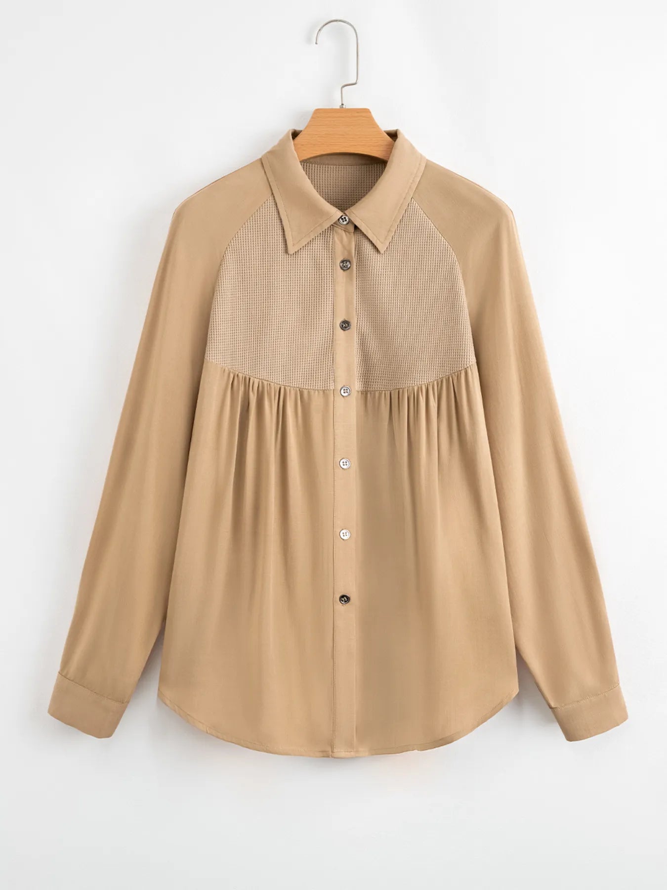Beige shirt with a textured collar on a hanger against a white background