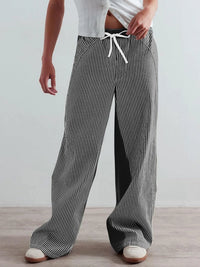 Person wearing black and white striped pants with a plain background