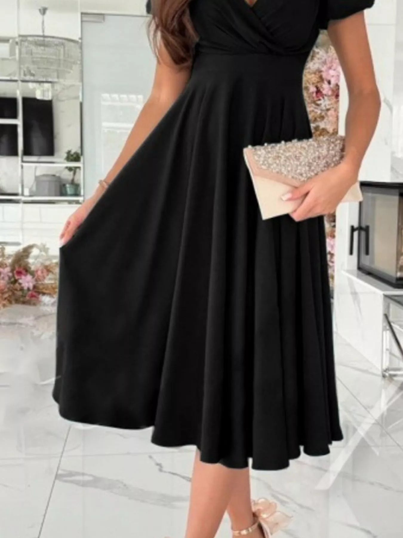Woman wearing a black dress holding a clutch in an indoor setting