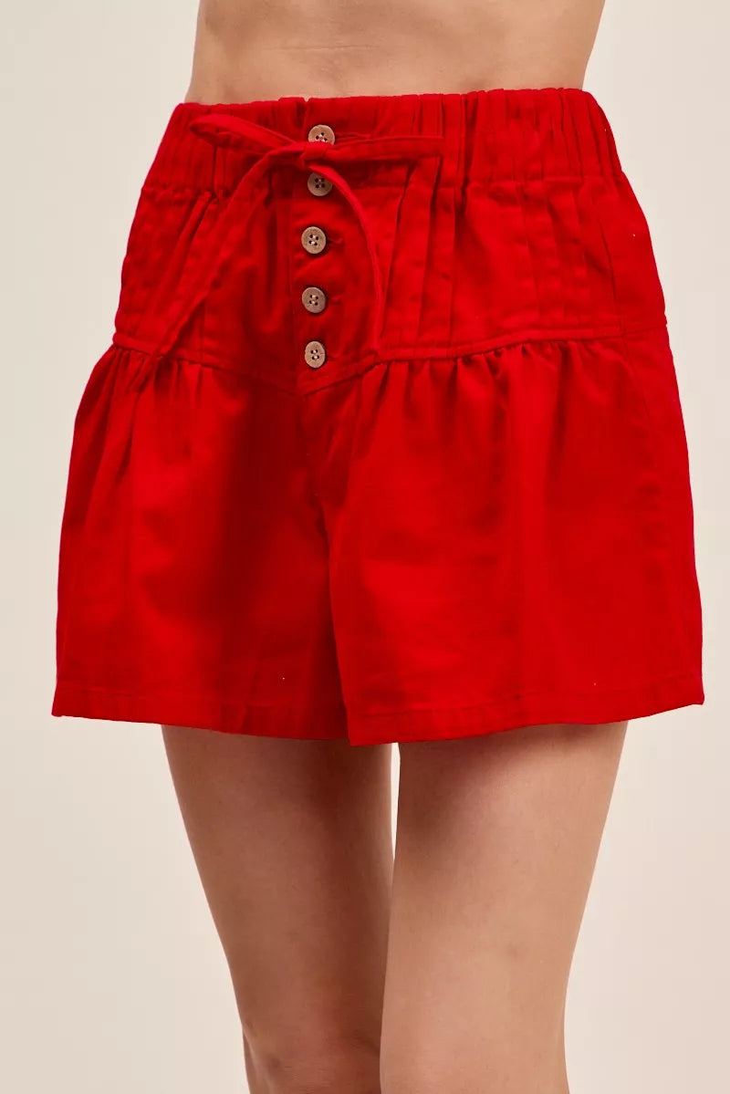 Red shorts with button details on a beige background