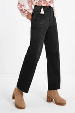 Person wearing black pants and tan boots on a white background