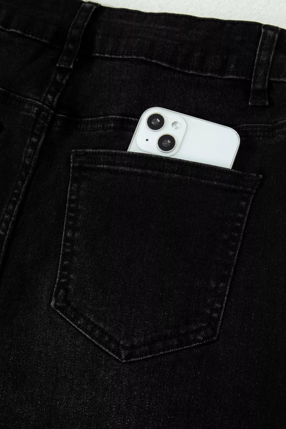 White smartphone in the pocket of black jeans