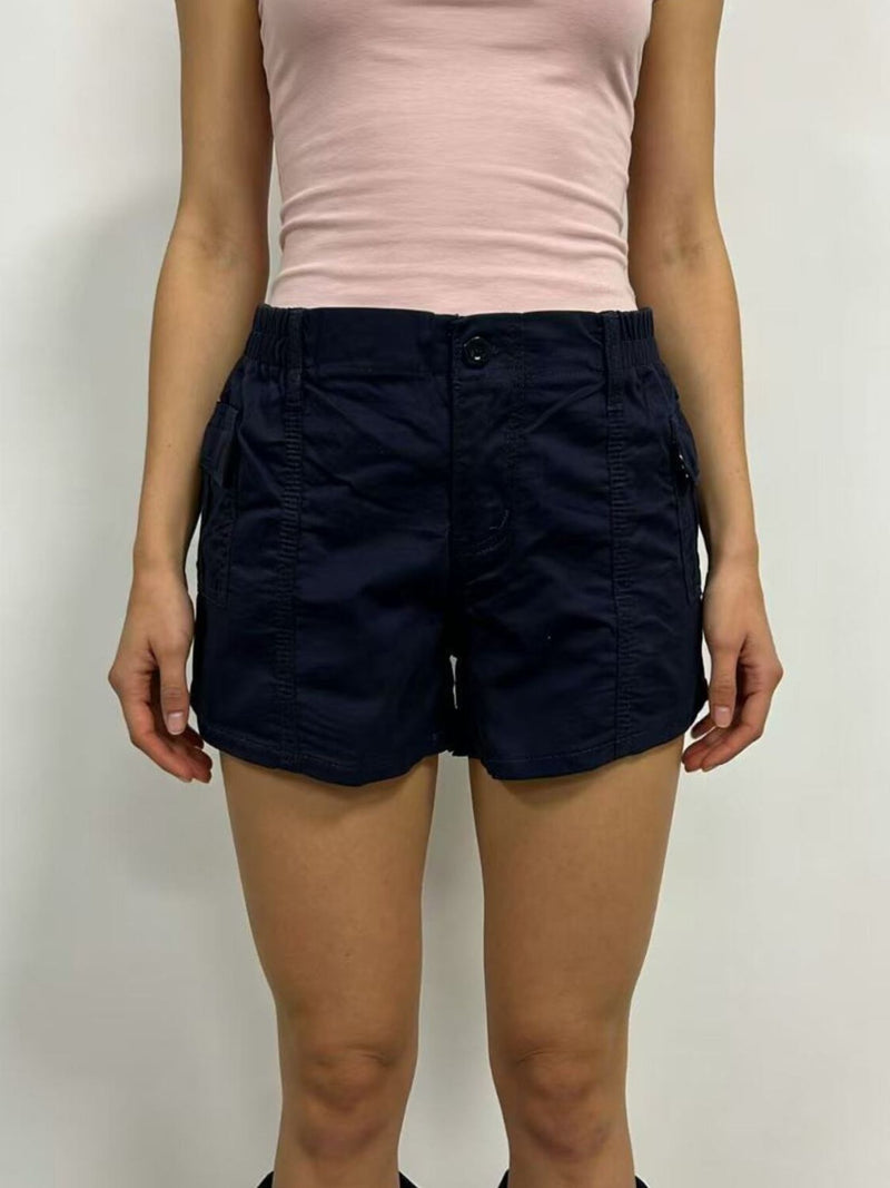 Person wearing navy shorts and a light pink top on a plain background