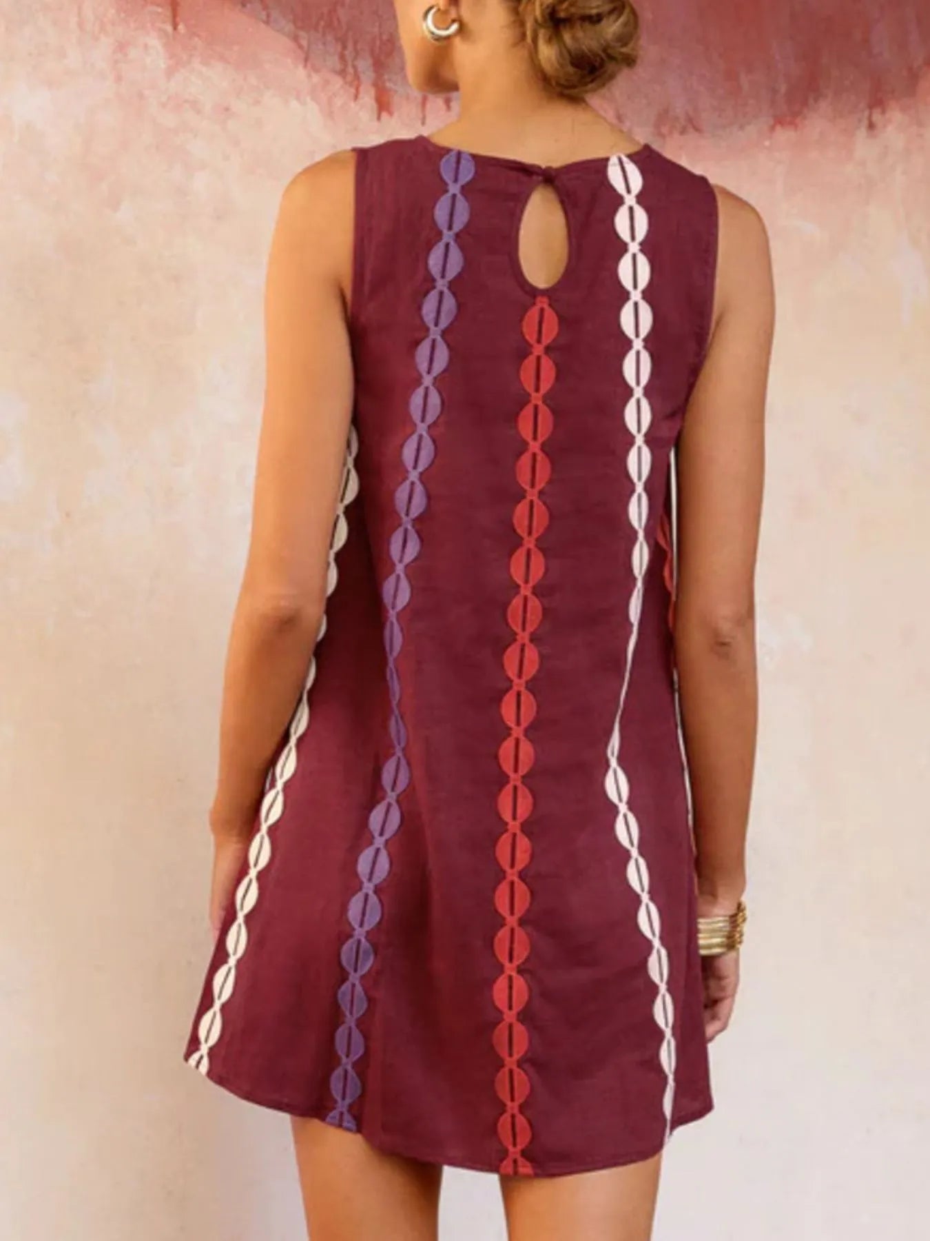 Maroon dress with colorful patterns on the back, worn by a person against a neutral background