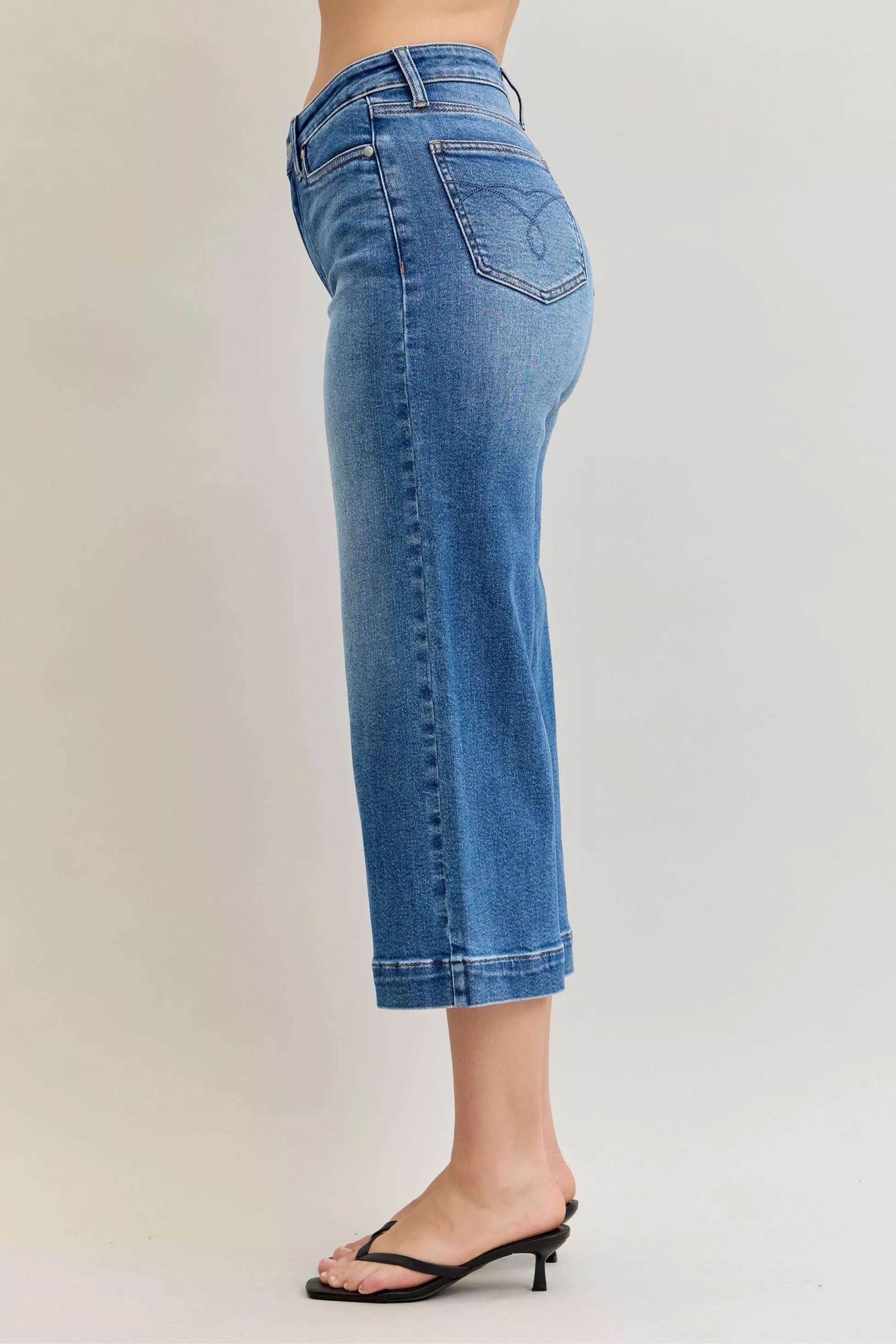 Blue jeans worn by a person on a plain background