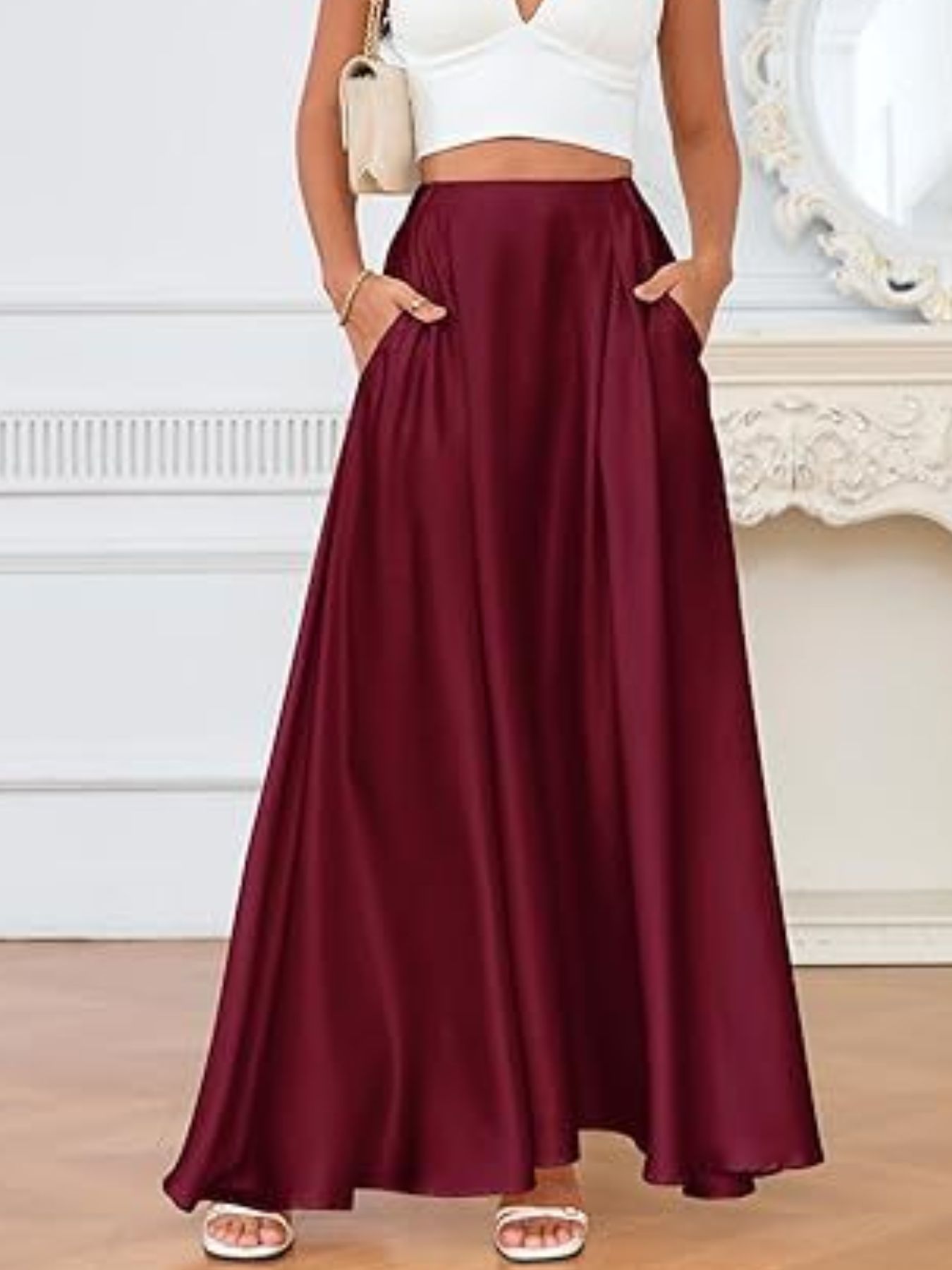 Person wearing a burgundy skirt with a white top and sandals indoors.