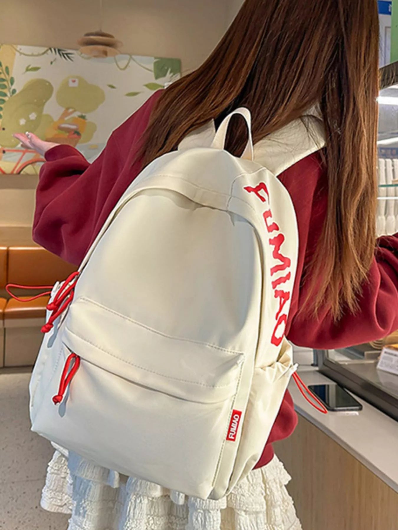 Person wearing a white backpack with red accents in an indoor setting